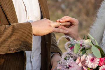 Obraz na płótnie Canvas Close-up hand of a bride puts a ring on a man's hand. Outside registration. Custom wedding