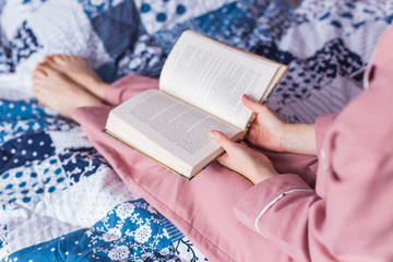 Close-up of woman wears pajama and relaxing at home and reading a book. Stay home. Quarantine pandemic coronavirus concept.