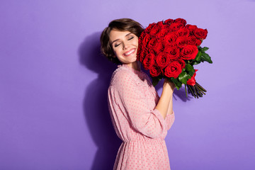 Portrait of nice-looking attractive cute charming cheerful cheery glad dreamy girl holding in hands roses fast shop delivery isolated on bright vivid shine vibrant lilac violet purple color background