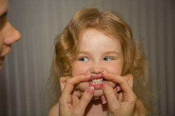 Little girl has blond hair, blue eyes, shows her teeth