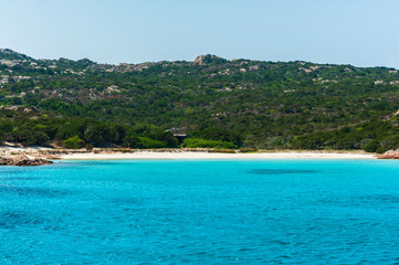A view from a sailboat of the crystal clear and colorful sea of ​​Budelli island with its famous and protected pink beach on a sunny day, in Budelli island Sardinia Italy
