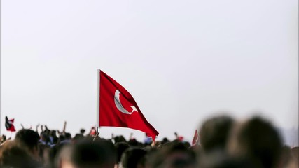 CGI Animated Turkish flag on the hand of a person and the day is September 9 Independence day of Izmir. Crowded people in the square of Gundogdu and Turkish flags in crowded people.