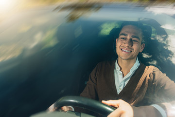 Young caucasian man smiling driving car. Glass reflection.
