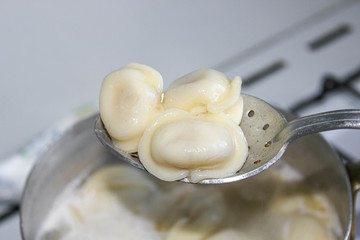 Boiled dumplings are pulled out of the pan with a skimmer.