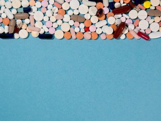 Group of pharmaceutical medicine pills, tablets and capsules on a blue background with copyspace.