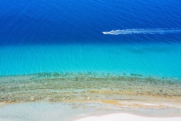 Aerial drone view motorboat in Port Glarokavos and lagoon beach in Kassandra penisula Chalkidiki Greece