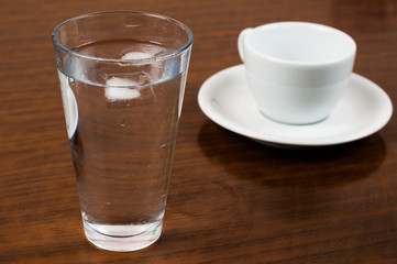 A glass and an ice cube on a wooden table