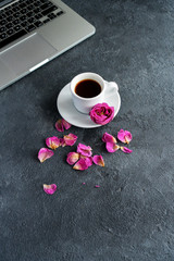 coffee mug and pink rose petals on a table on a black background