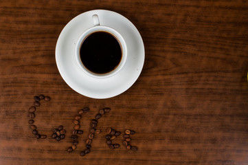 White coffee cup and coffee beans on a wooden table.Coffee time