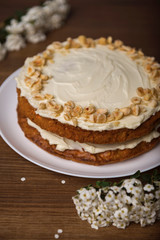 Carrot cake and branch with white flowers on the wooden table