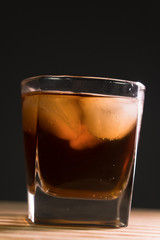 Glass of whiskey on wooden background close up