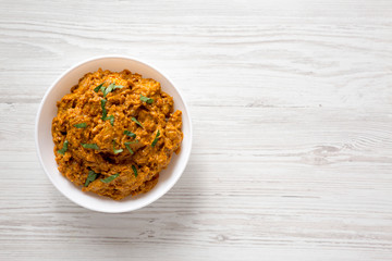 Homemade Chicken Tikka Masala in a white bowl on a white wooden table, top view. Flat lay, overhead, from above. Copy space.