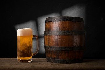 Beer barrel with beer glasses on a wooden table. The dark brown background.