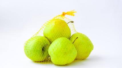 A group of apples in a orange mesh hanging in front of a white wall. Trend. The concept of diet and healthy eating green Granny Smith and golden
