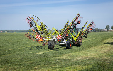 Making hay. Hay making machine. Summer, Grass drying. Farming. Tractor. Cattle feed. Steenwijkerland Netherlands