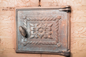 the iron door in the stove of brick with handle and patterns texture