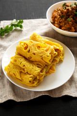 Homemade Net Crepe Roti Jala on a white plate on a black background, low angle view.