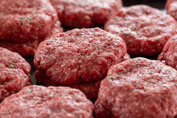 Multiple stacks of freshly processed raw hamburger patties on display in meat processing plant