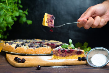 pie with black currant and shortbread, fresh berries. the pie is cut into pieces and the top is sprinkled with powdered sugar . close-up of a piece in the pie section