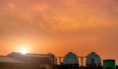 Fototapeta na wymiar Industrial gas storage tank. LNG or liquefied natural gas storage tank. Red and orange sunset sky. Spherical gas tank in petroleum refinery. Above-ground storage tank. Natural gas storage industry.