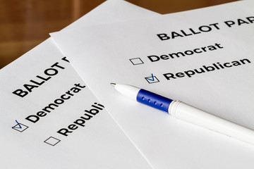 Obraz premium Checklist concept. Closeup of ballot papers with words Democrat and Republican and a pen on them. A checkmarks for Republican and Democrat in the checkboxes.