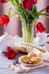 Tasty apple muffins with a beautiful bouquet of red tulips on a wooden background.