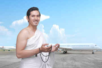 Asian Muslim man in ihram clothes with prayer beads on his hands