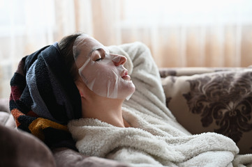 girl in a moisturizing facial mask lies on a sofa