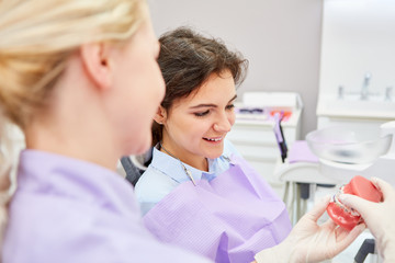 Zahnarzthelferin zeigt Patientin eine Zahnspange
