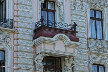 Fototapeta premium one old open brown balcony with black wrought iron bars on the concrete wall of a historic building with windows
