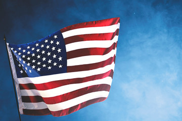 Fototapeta premium American flag waving in the air with a blue background