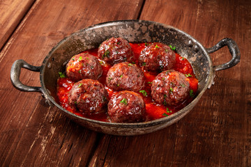 Meatballs with tomato sauce, a close-up in a pan on a dark rustic wooden background