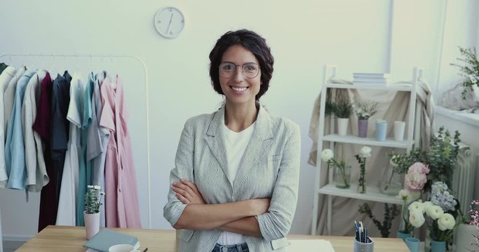 Confident smiling young adult business woman designer, florist, creative occupation specialist or fashion clothing store owner posing in modern studio looking at camera with arms crossed. Portrait.