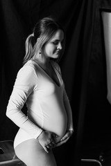 Beautiful pregnant woman in the bodysuit in the studio, Black and white photo of a pregnant woman in the bodysuit.