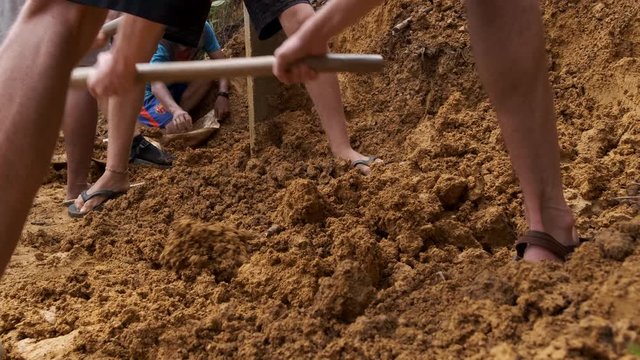 Handheld shot of villager moving clay soil with hand tools, Indonesia