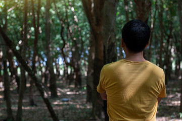 The male tourists standing with their crossed arms and happy to look at nature in front of them while standing in the forest.