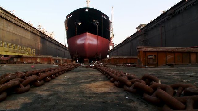 Trucking shot of a supertanker in dry dock with the sea drained out