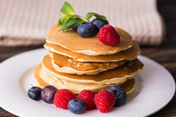 Pancakes with blueberries and raspberry on wooden background. Breakfast and traditional meal.