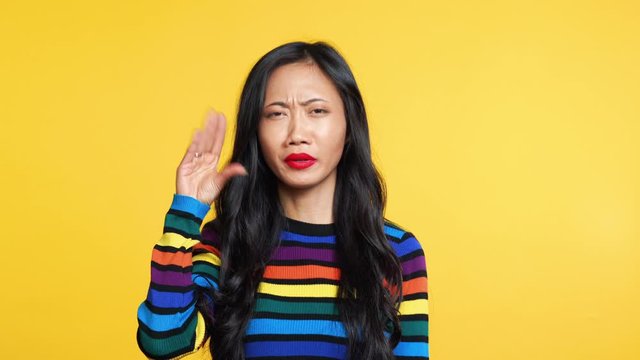 Boring asian woman showing bla-bla-bla gesture with hands looking to camera