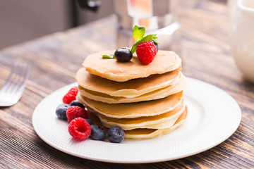 Pancakes with blueberries and raspberry on wooden background. Breakfast and traditional meal.