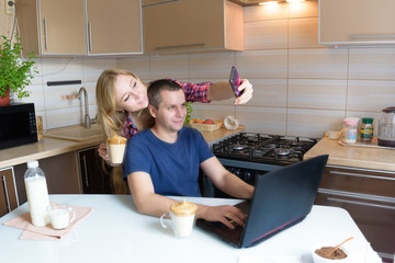 a man and a woman with a laptop communicate online, sitting in the kitchen with dalgona coffee . freelance at home. concept of social distance, work at home, online communication, virtual friends