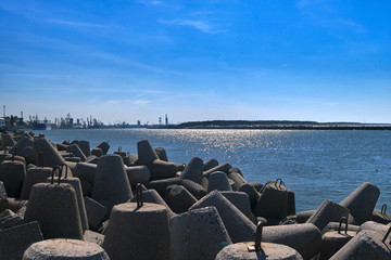 View of a harbor over modular concrete block ripraps in foreground and port in background on sunny...