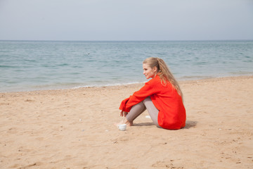 Beautiful blonde woman sits on a beach alone