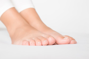 Young, perfect, clean female feet relaxing on bed. Closeup.