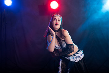 Young woman belly dancer in exotic dress with gold, dancing tribal fusion dance in studio.