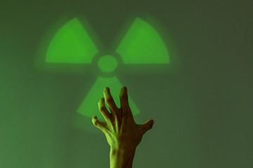 The male hand touches the sign of radiation hazard. Green background. Copy space.