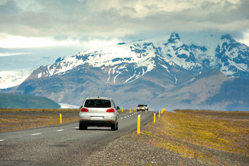 The car is running on the highway. In the countryside in Iceland The background is a great and exciting mountain. Road trip concepts and driving in traveling.