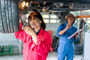 Senior Man and Woman Mechanic Examining Under the Car at the Repair Garage.