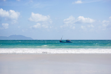 Vietnamese fishing boat in the azure sea with sea waves on a background of blue sky. Doc Let beach