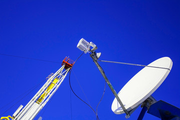 Satellite dish on the background of blue sky and oil rig.